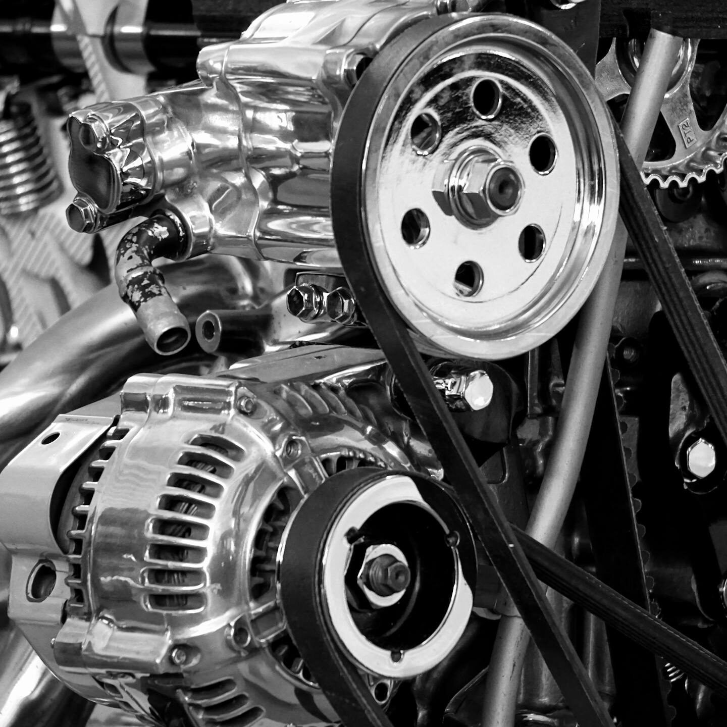 Close-up of a shiny car engine showing polished metal parts and gears in black and white.